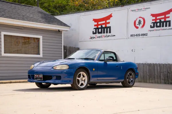 Blue Mazda Miata convertible parked outside.