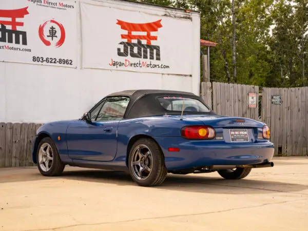 Blue Mazda Miata convertible parked.