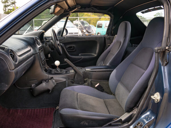 Black interior of a blue convertible car.