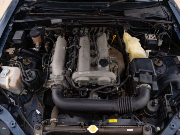 Engine bay of a blue Mazda Miata.