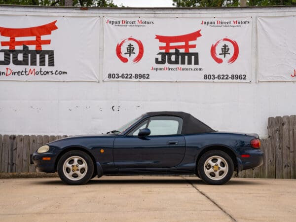 Blue convertible Mazda Miata parked outdoors.