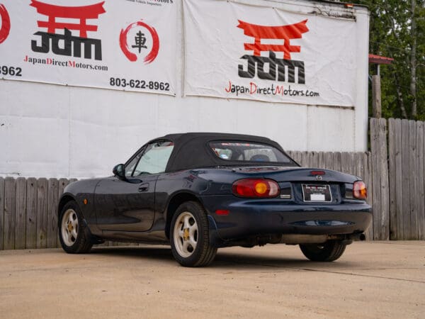 Blue convertible Mazda Miata parked.