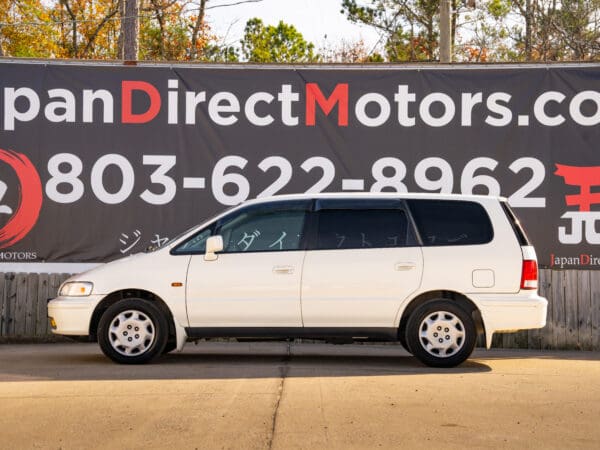 White Honda Odyssey minivan, side view.