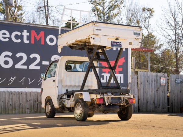 White Daihatsu mini-truck with lift.