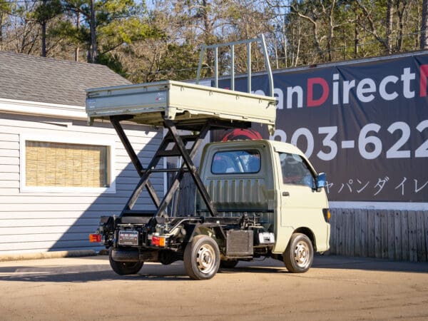 Light green mini dump truck, rear view.