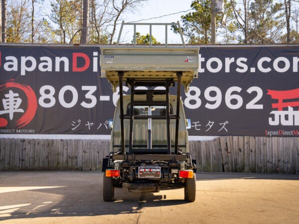 Here's an 8-word alt tag for the image: Rear view of a light green dump truck.