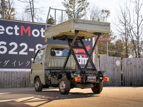 Here's an alt tag for the image: Green mini dump truck with lift.